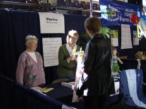 Thrive volunteers talk with a visitor at an exposition booth in 2007.
